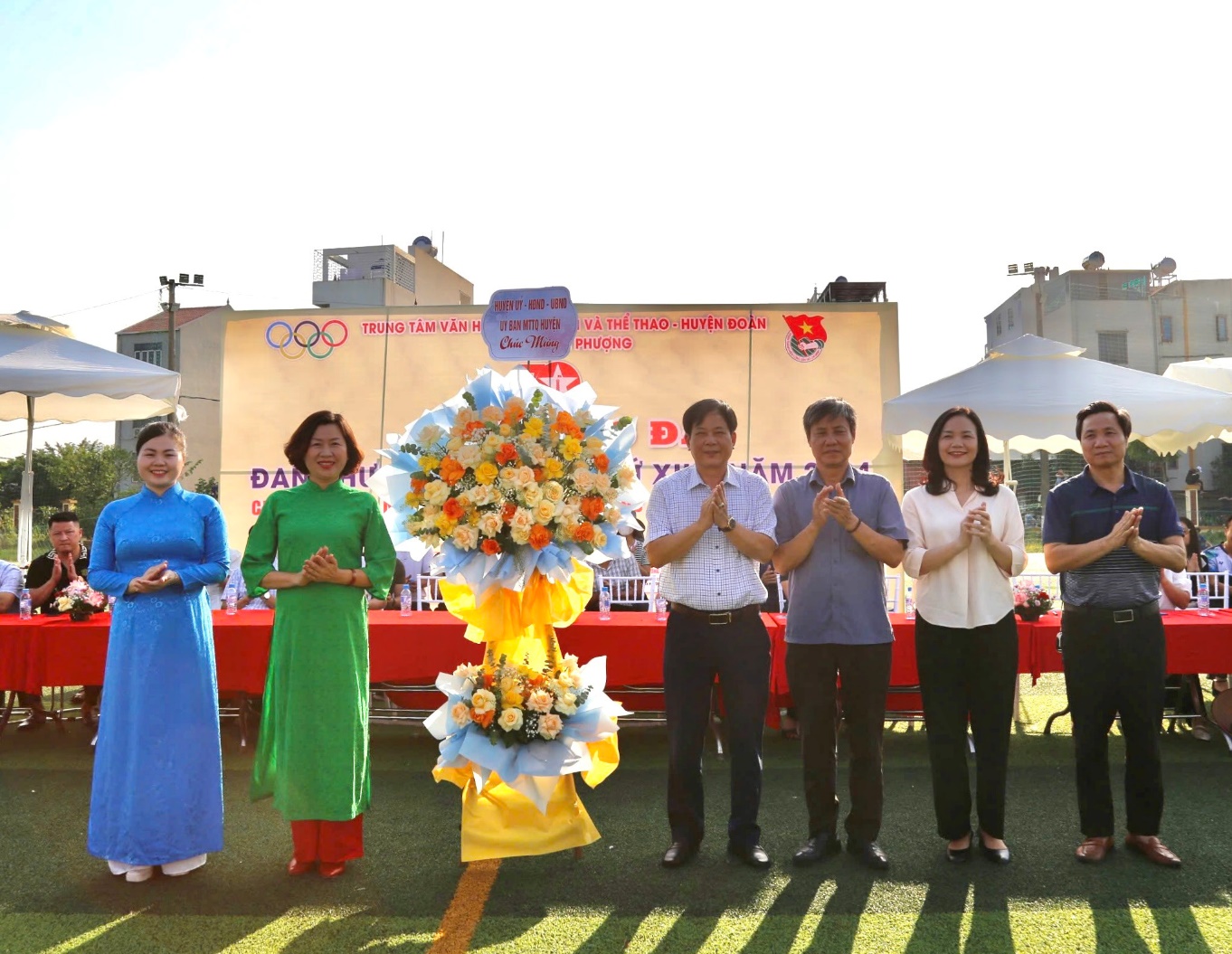 A group of people standing in a line with flowers  Description automatically generated