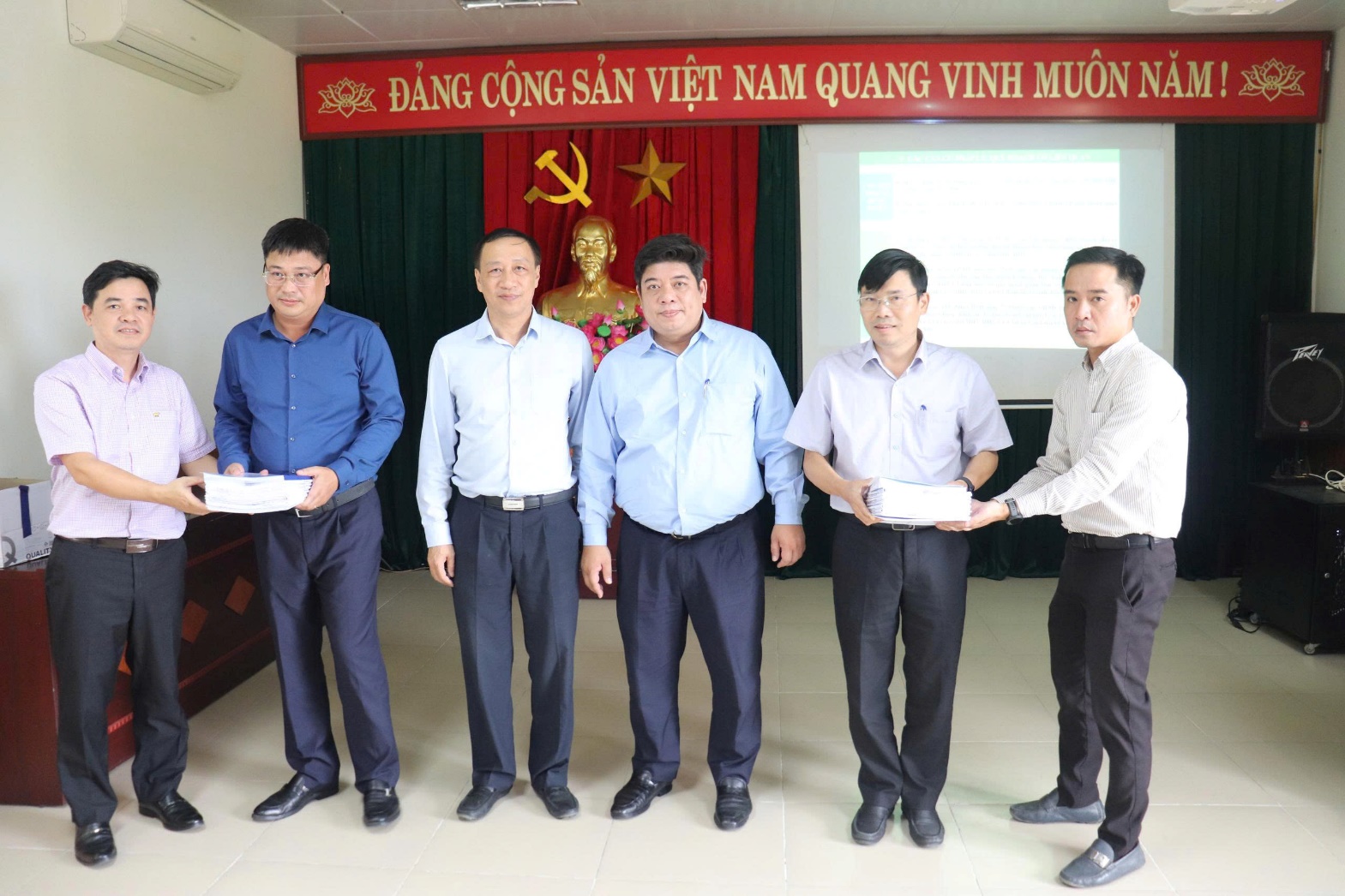 A group of men standing in front of a red and white banner  AI-generated content may be incorrect.