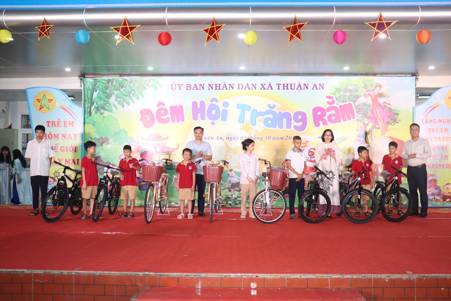 A group of children standing on a stage with bicycles  AI-generated content may be incorrect.