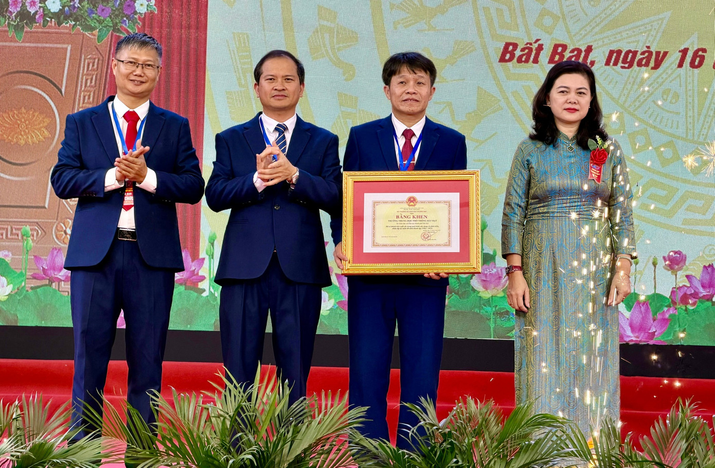 A group of people standing on a stage with a framed picture  Description automatically generated