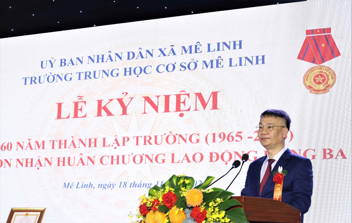 A person standing at a podium with a microphone  AI-generated content may be incorrect.