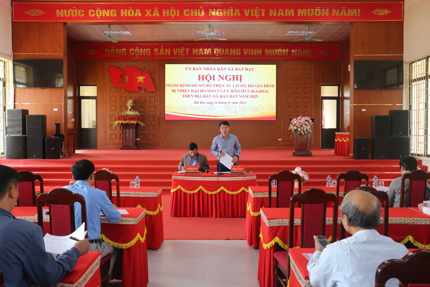 A person speaking to a group of people in a room  Description automatically generated