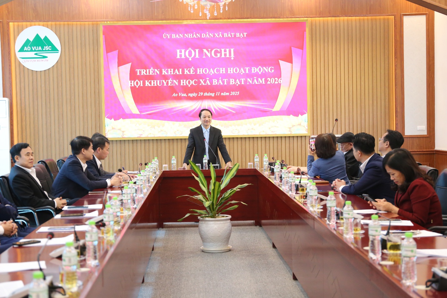 A person standing in front of a group of people sitting at a table  Description automatically generated