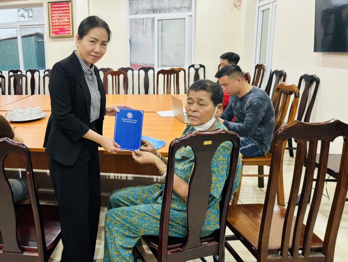 A person holding a book to a person sitting in a chair  AI-generated content may be incorrect.