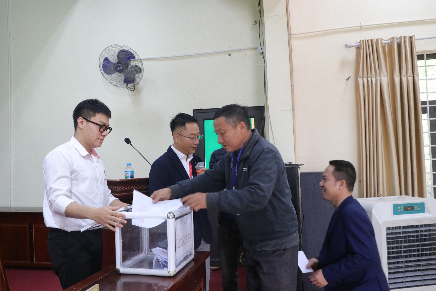 A group of men standing around a ballot box  AI-generated content may be incorrect.