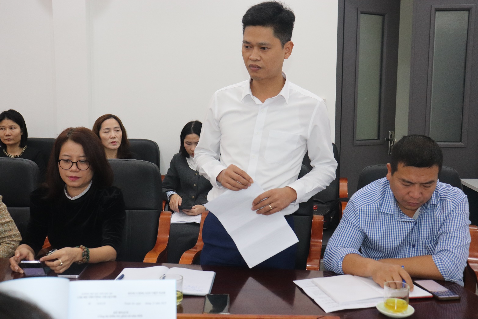 A person standing in front of a table with papers  AI-generated content may be incorrect.