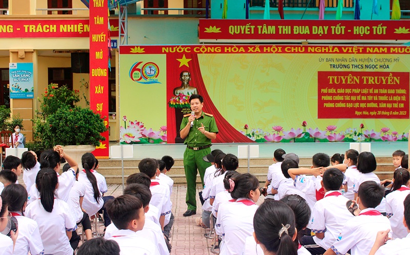 A person in a green uniform speaking to a group of children  AI-generated content may be incorrect.