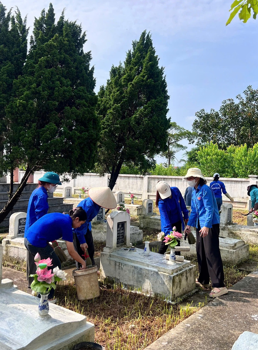 A group of people in blue shirts and hats cleaning a grave  AI-generated content may be incorrect.