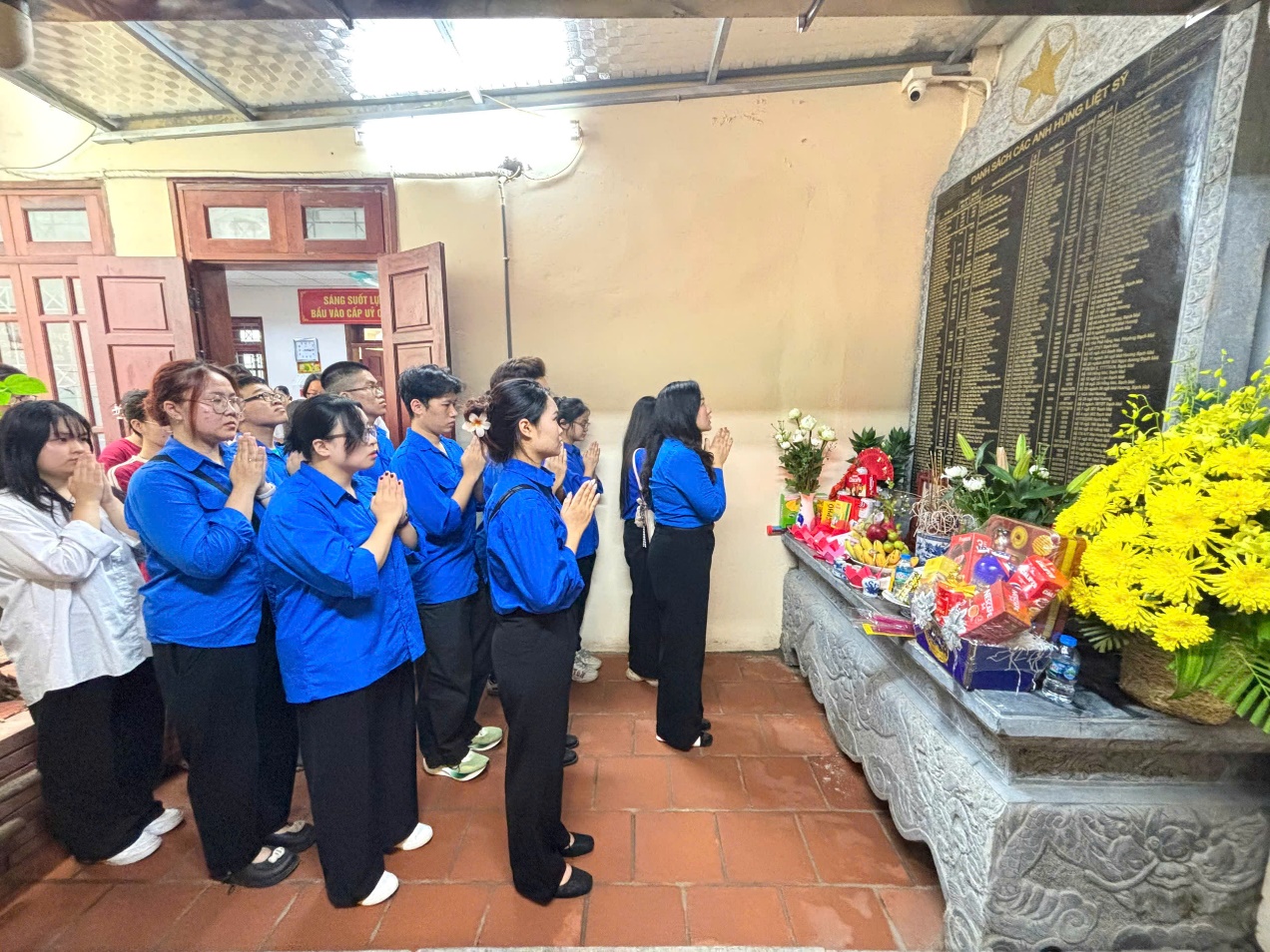 A group of people standing in front of a memorial  Description automatically generated