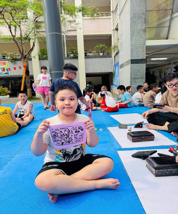 A child sitting on a blue mat holding a sign  AI-generated content may be incorrect.