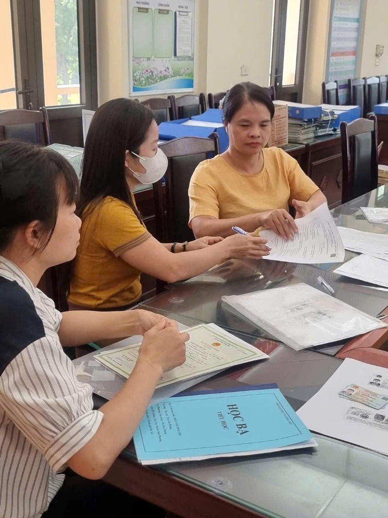 A group of people sitting at a table with papers  AI-generated content may be incorrect.