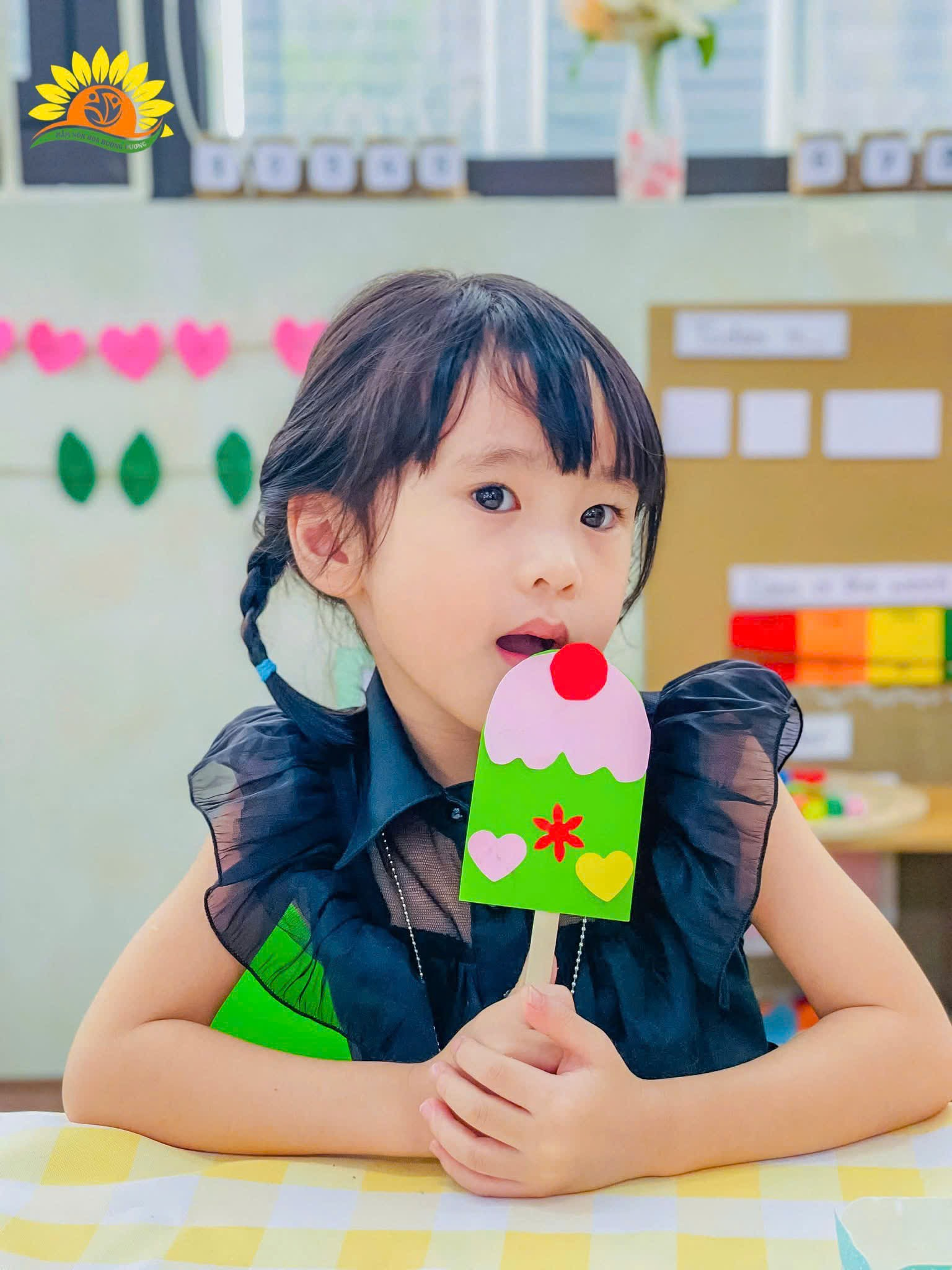 A child holding a paper ice cream  Description automatically generated