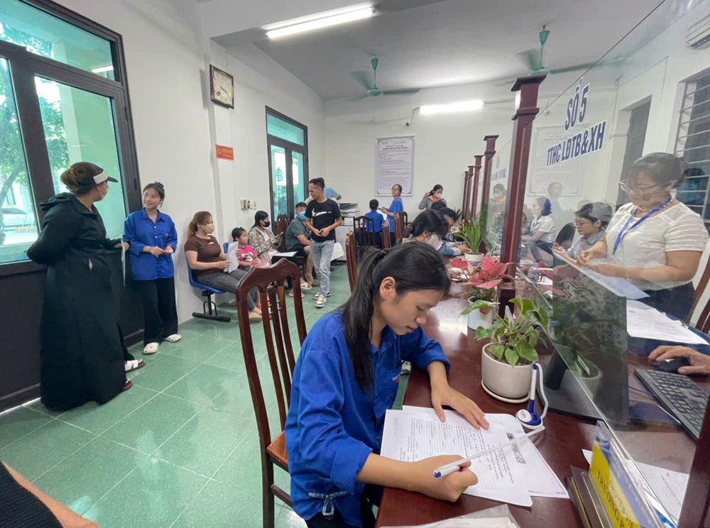 A person writing on a paper in a room with other people  AI-generated content may be incorrect.