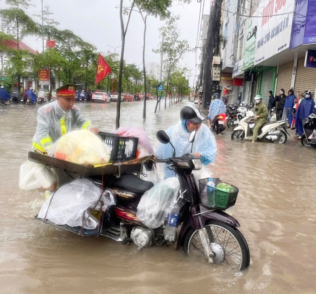 Công an xã Hoài Đức tăng cương đảm bảo an toàn giao thông, hỗ trợ người dân qua các điểm ngập úng- Ảnh 1.