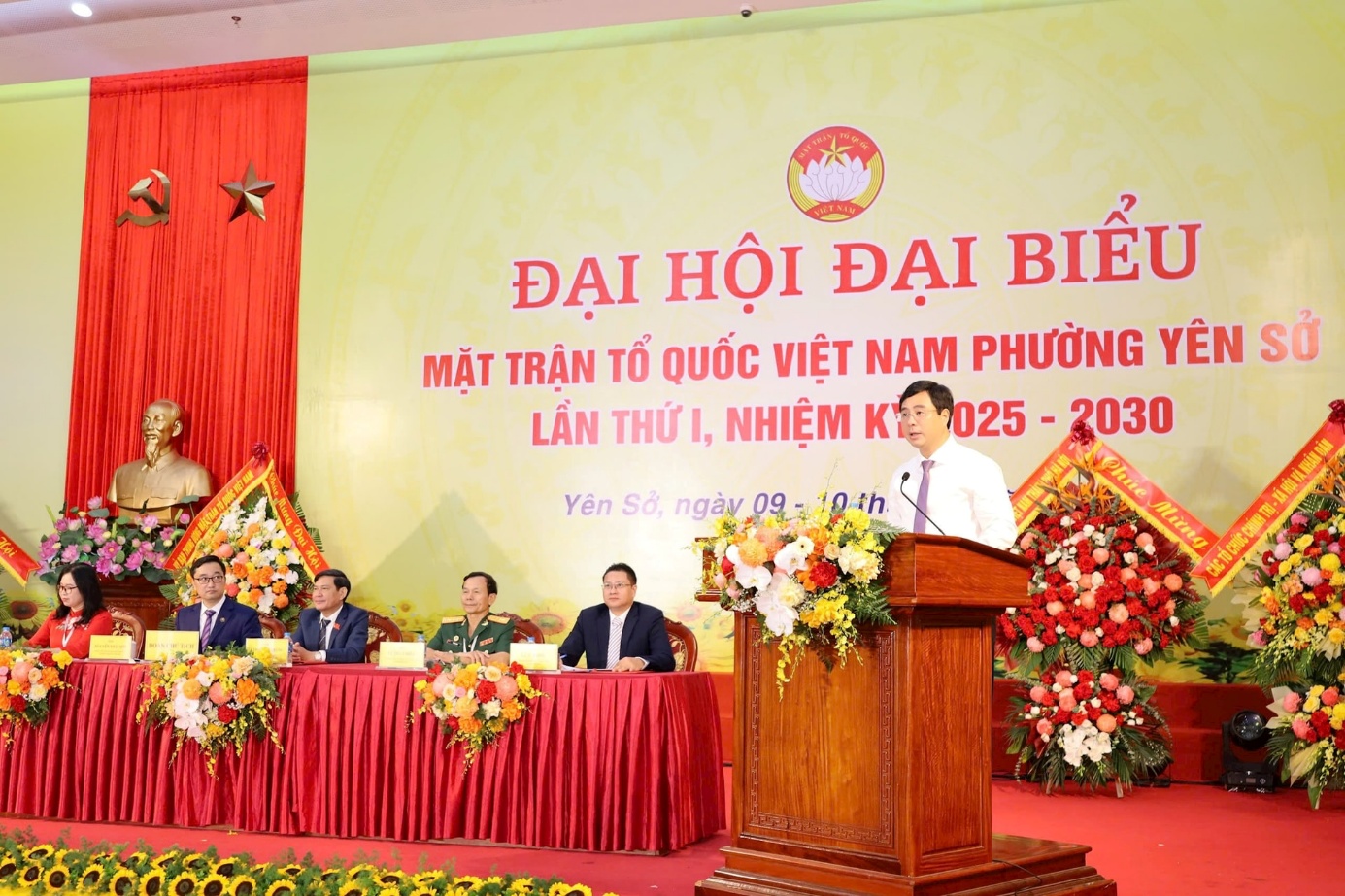 A person standing at a podium with a podium and flowers  AI-generated content may be incorrect.