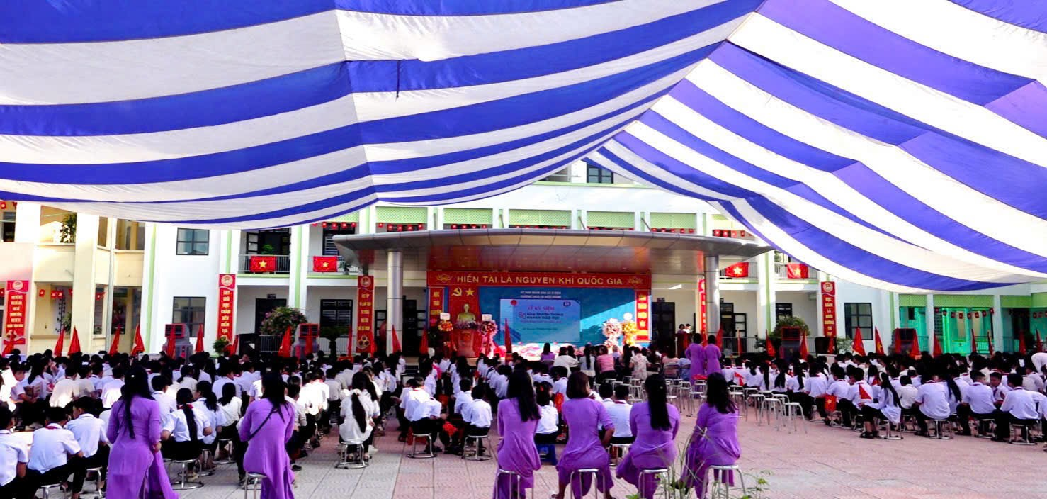 A group of people in purple dresses sitting in chairs under a blue and white striped tent  Description automatically generated