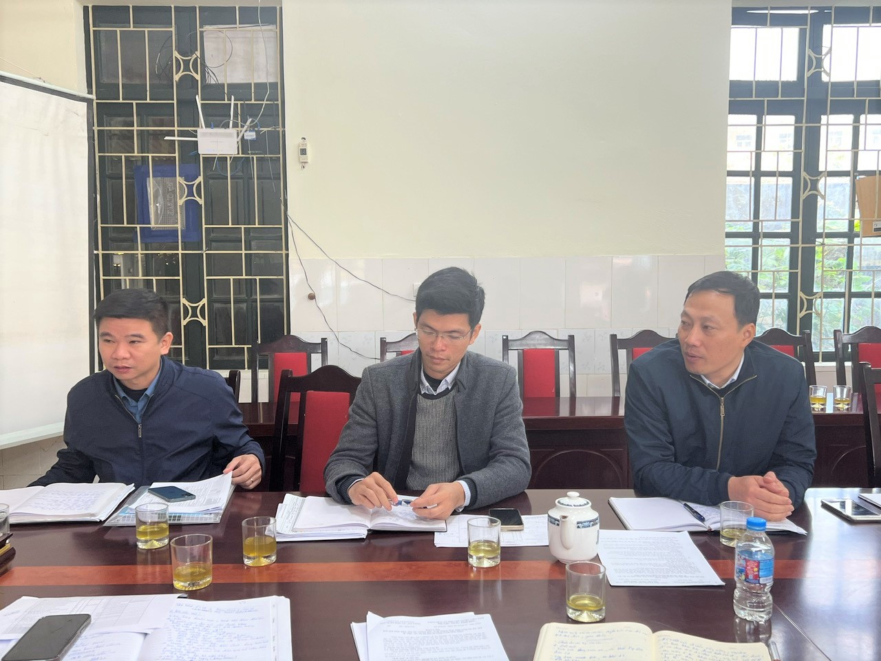 A group of men sitting at a table with papers  AI-generated content may be incorrect.