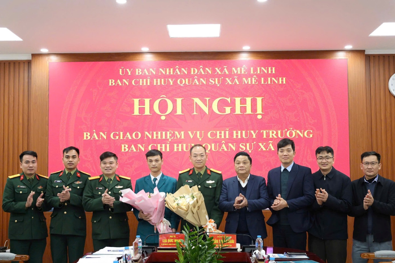 A group of men in military uniforms standing in front of a banner  AI-generated content may be incorrect.