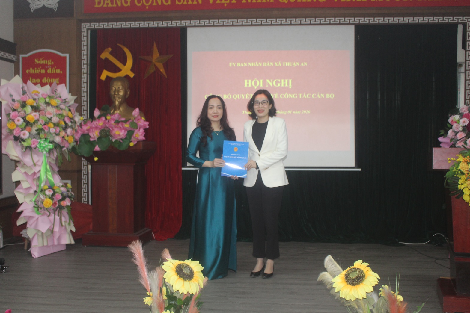 A person holding a blue paper and standing next to another person  AI-generated content may be incorrect.