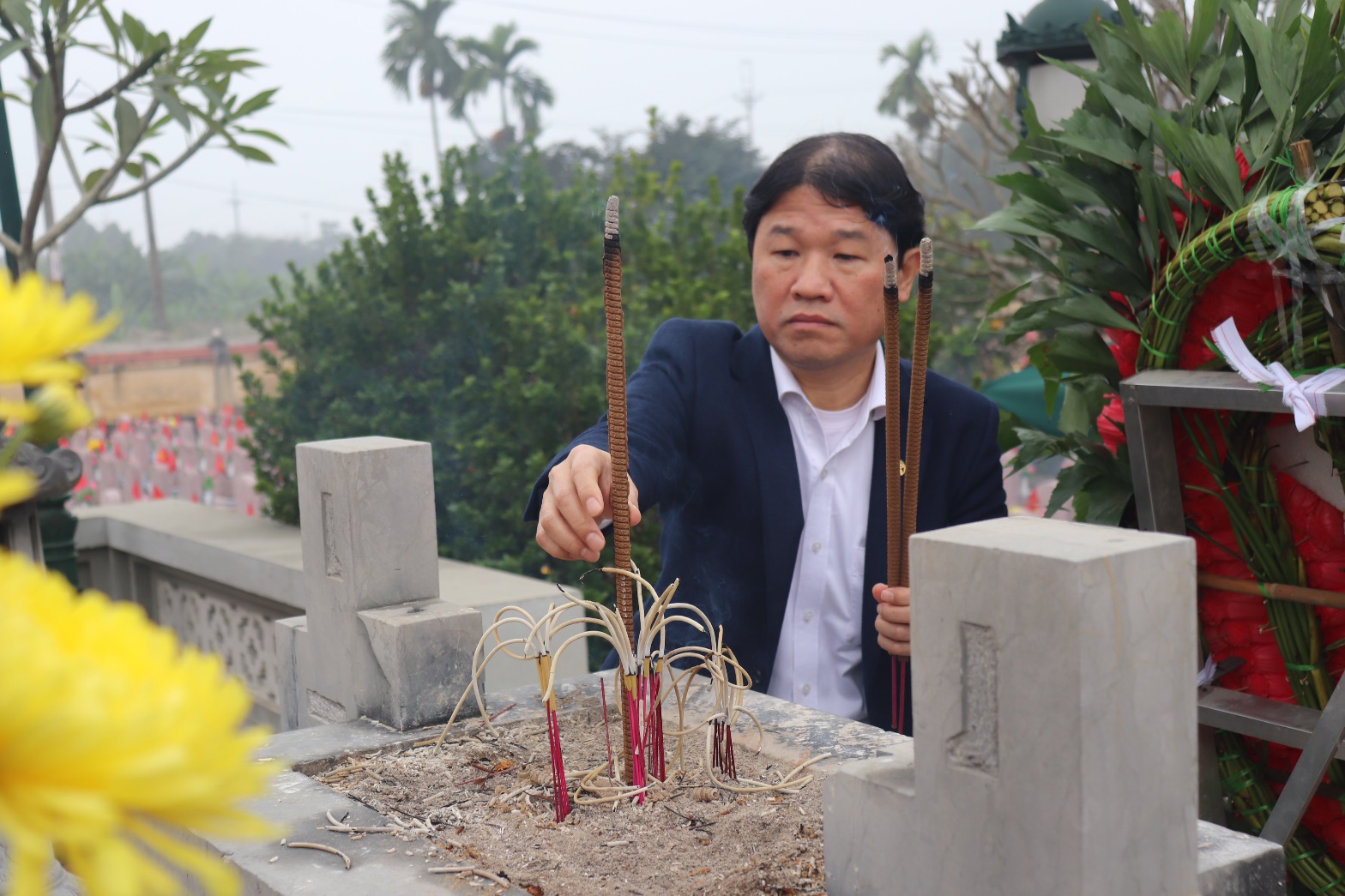 A person holding sticks in front of a grave  AI-generated content may be incorrect.