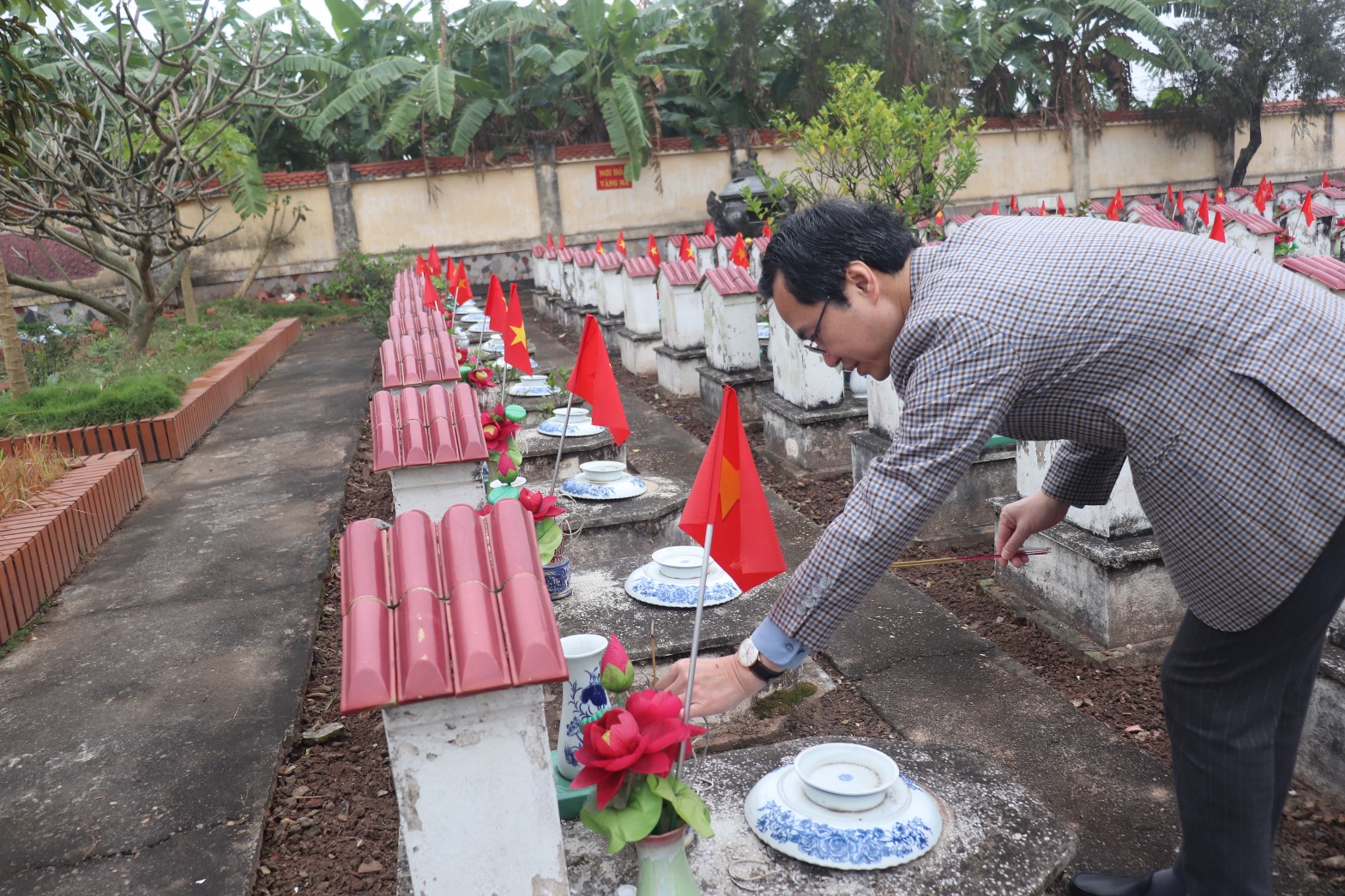 A person placing flowers on a grave  AI-generated content may be incorrect.