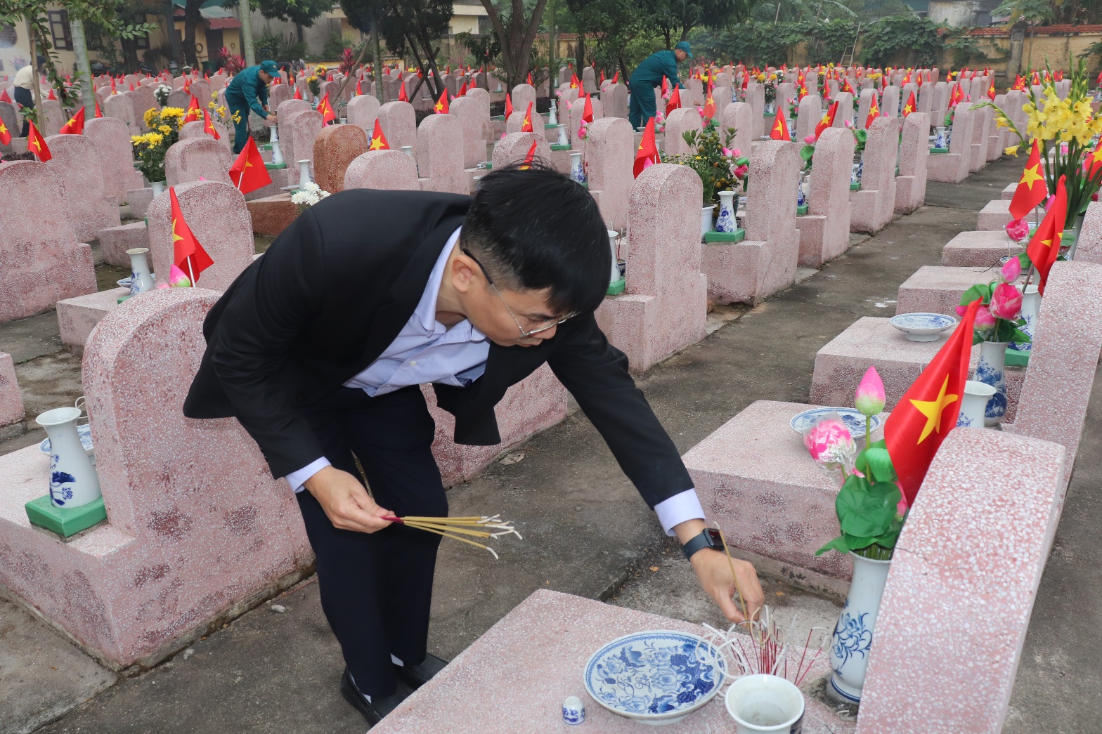 A person lighting incense sticks in a cemetery  AI-generated content may be incorrect.
