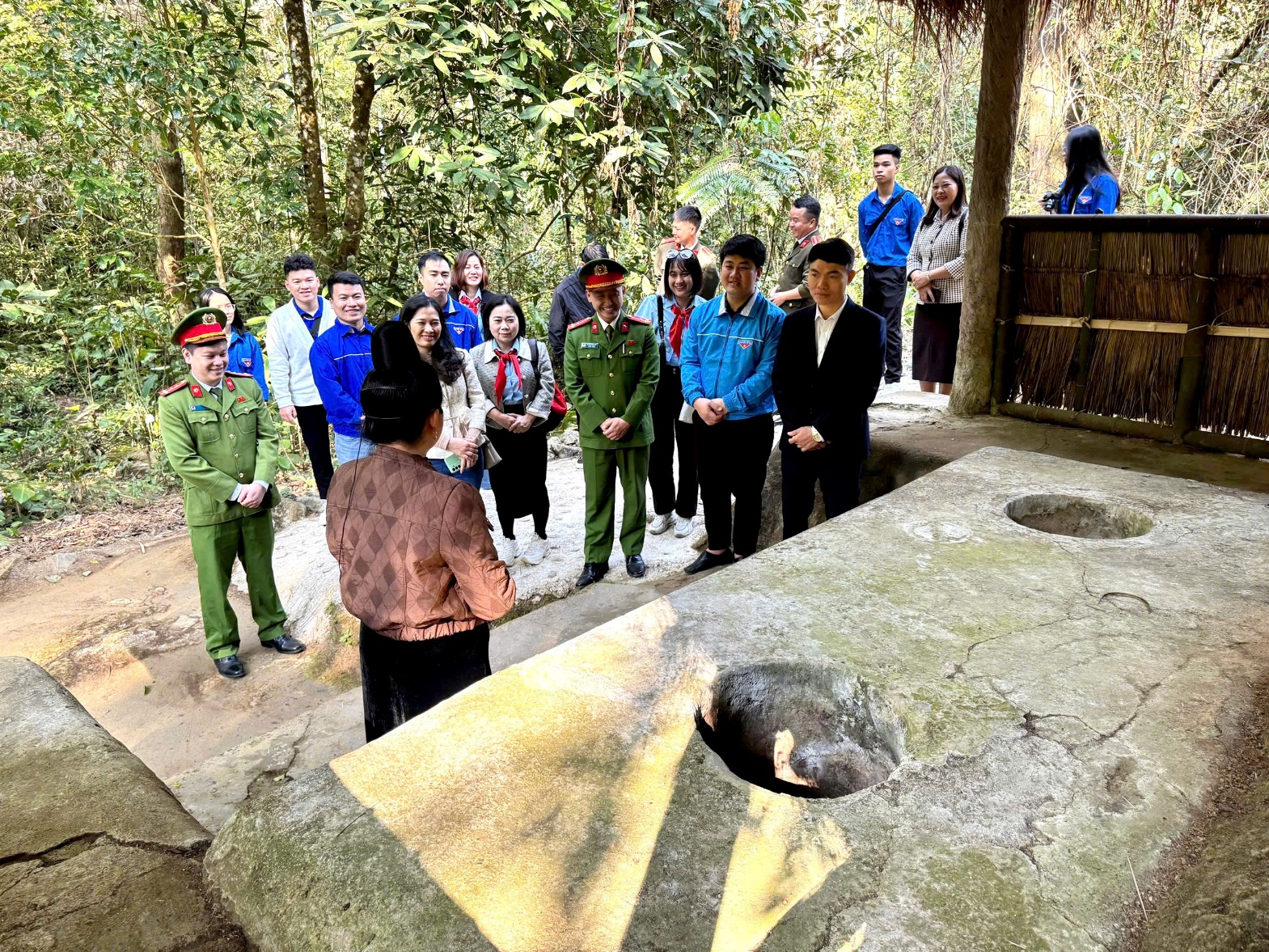 A group of people standing around a stone structure  AI-generated content may be incorrect.