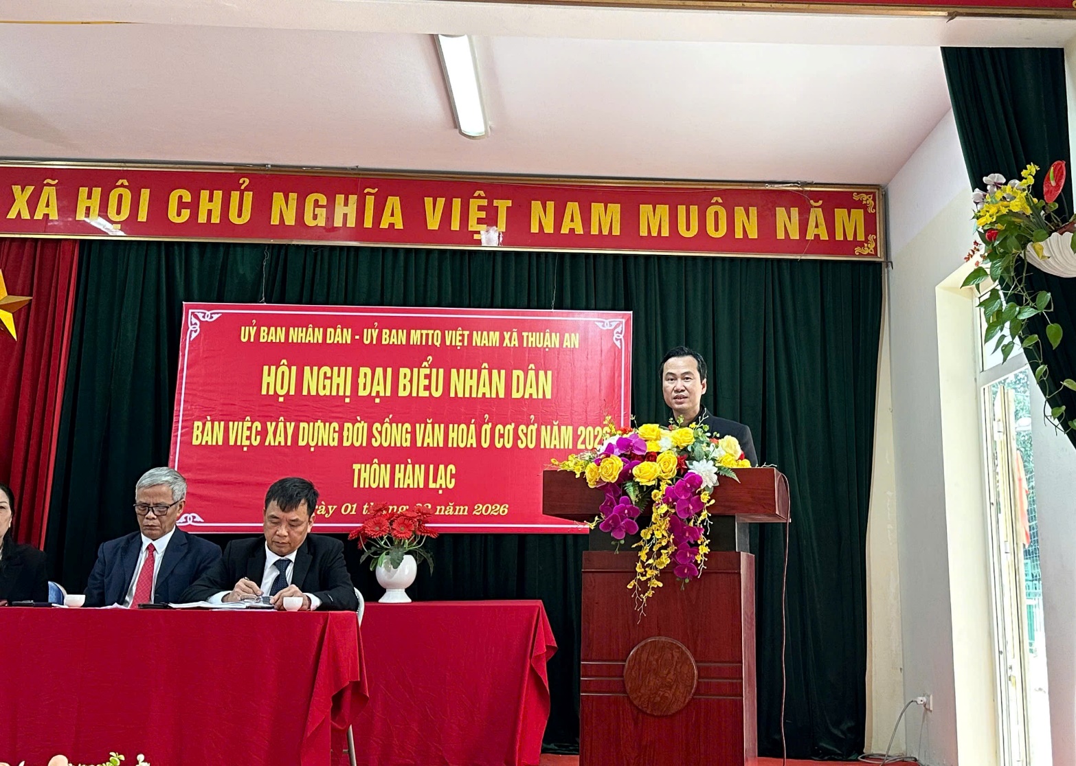 A person standing at a podium with a group of men sitting at a podium  AI-generated content may be incorrect.