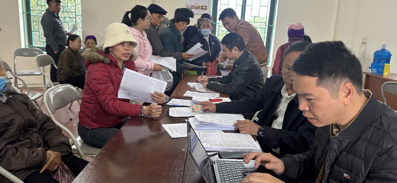 A group of people sitting at a table with papers  AI-generated content may be incorrect.