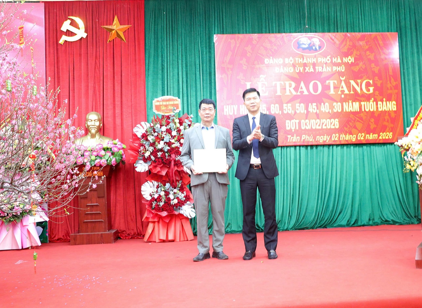 A person standing on a stage with a sign on the wall  AI-generated content may be incorrect.