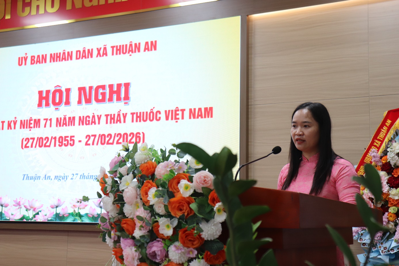 A person standing at a podium with a microphone and flowers  AI-generated content may be incorrect.