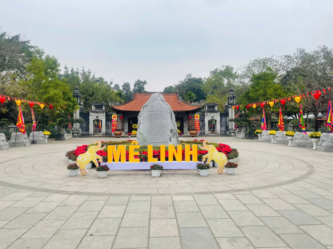 A stone monument with flowers and flags in front of a building  AI-generated content may be incorrect.