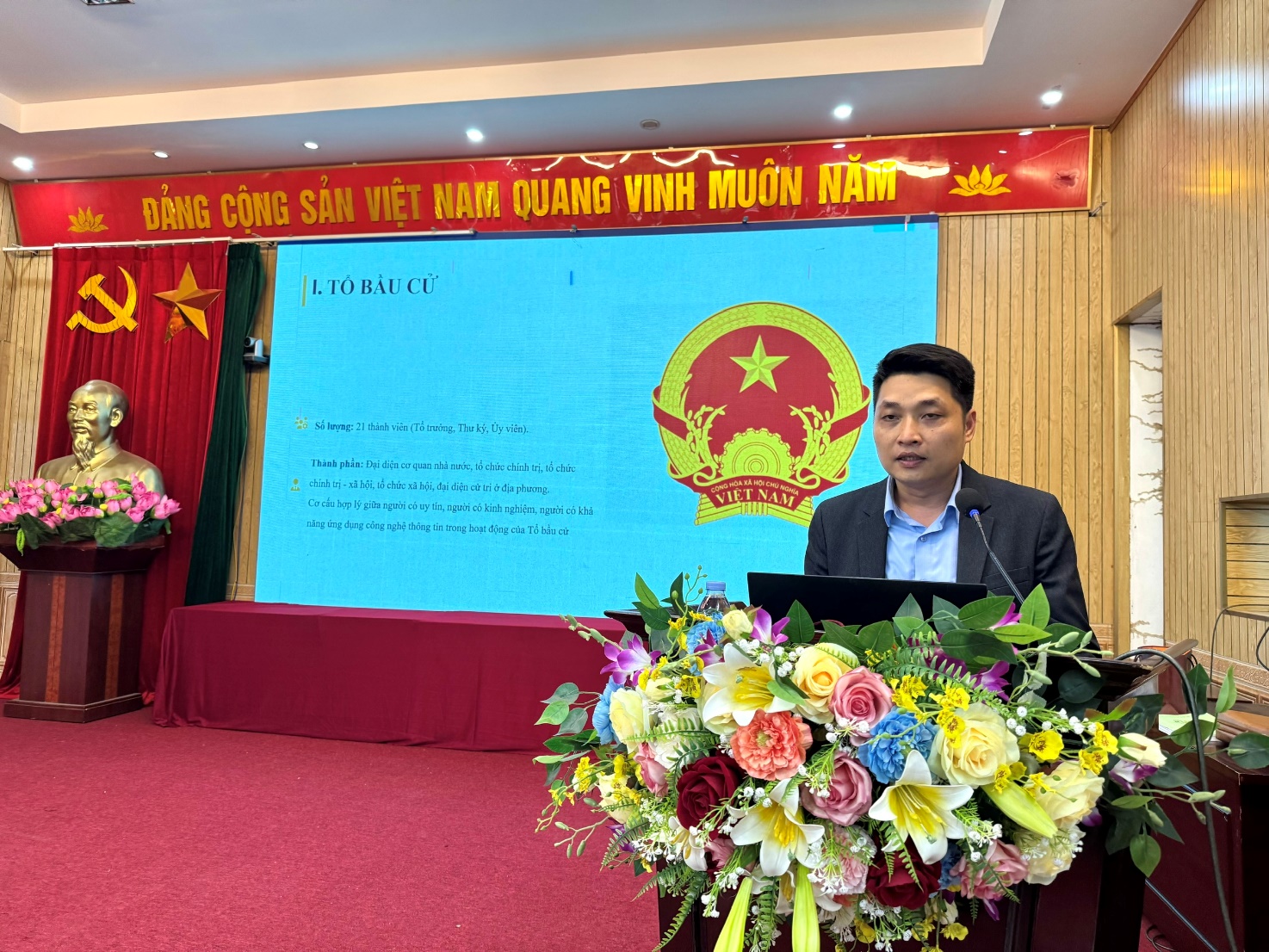 A person standing at a podium with flowers  AI-generated content may be incorrect.