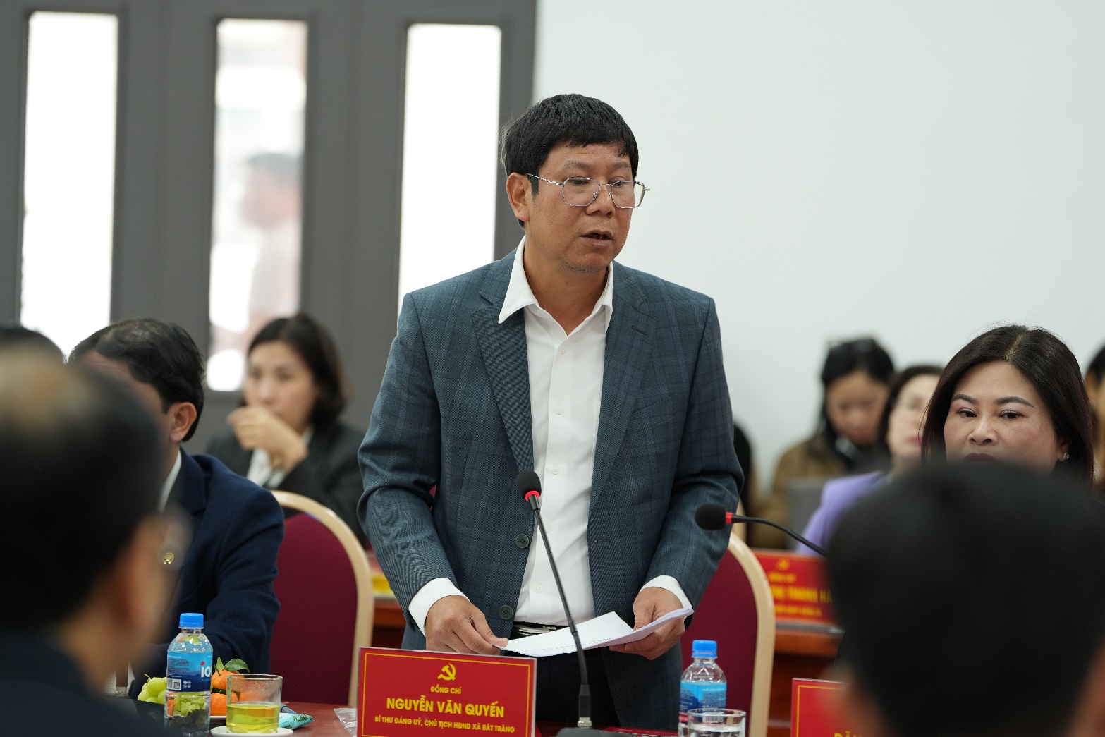 A person in a suit standing at a podium  AI-generated content may be incorrect.