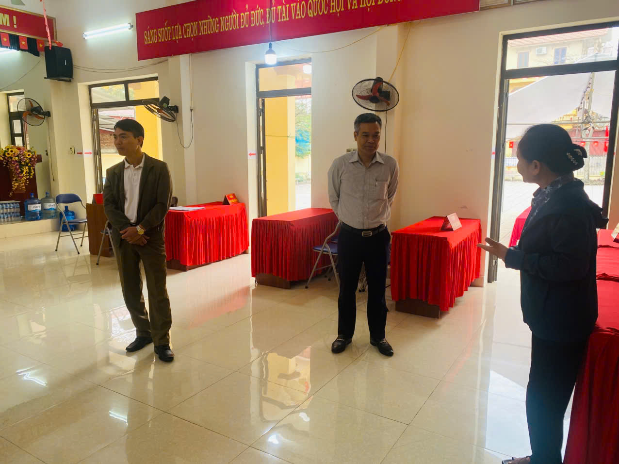 A group of people standing in a room with red tablecloths  AI-generated content may be incorrect.