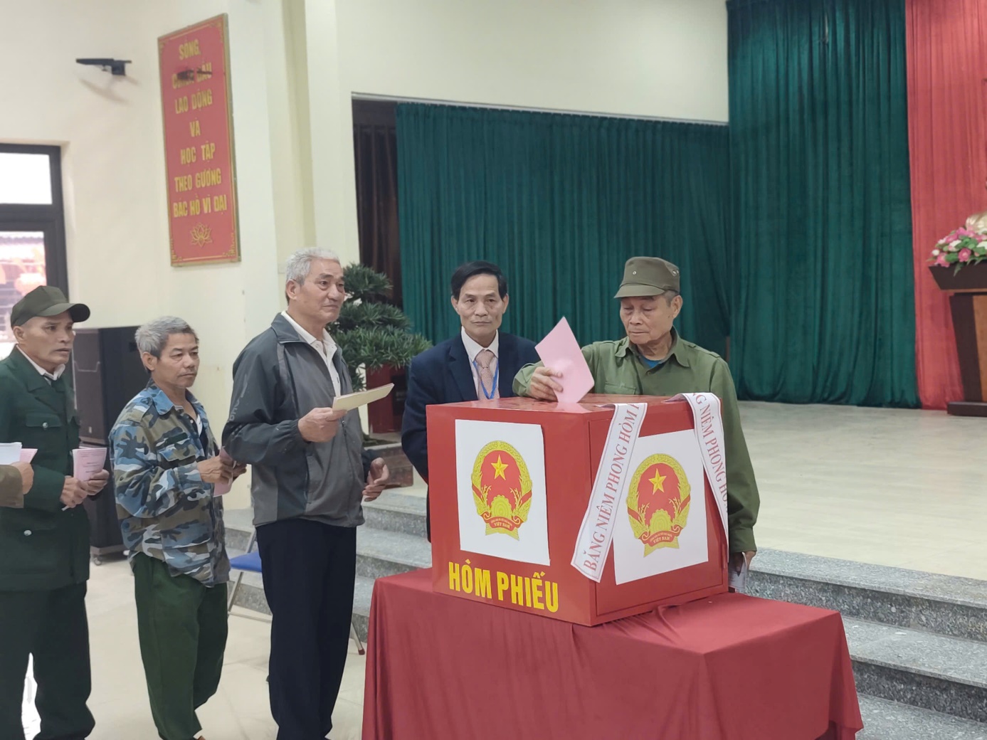 A group of men standing next to a box with a red tablecloth  AI-generated content may be incorrect.