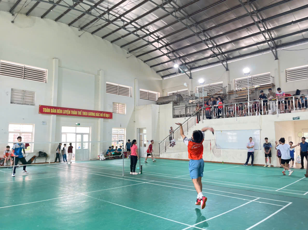 A person playing badminton in a gym  AI-generated content may be incorrect.