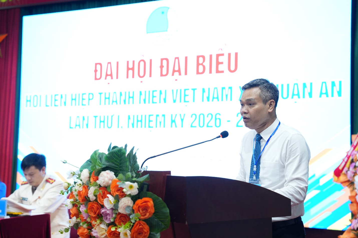 A person standing at a podium with a microphone  AI-generated content may be incorrect.