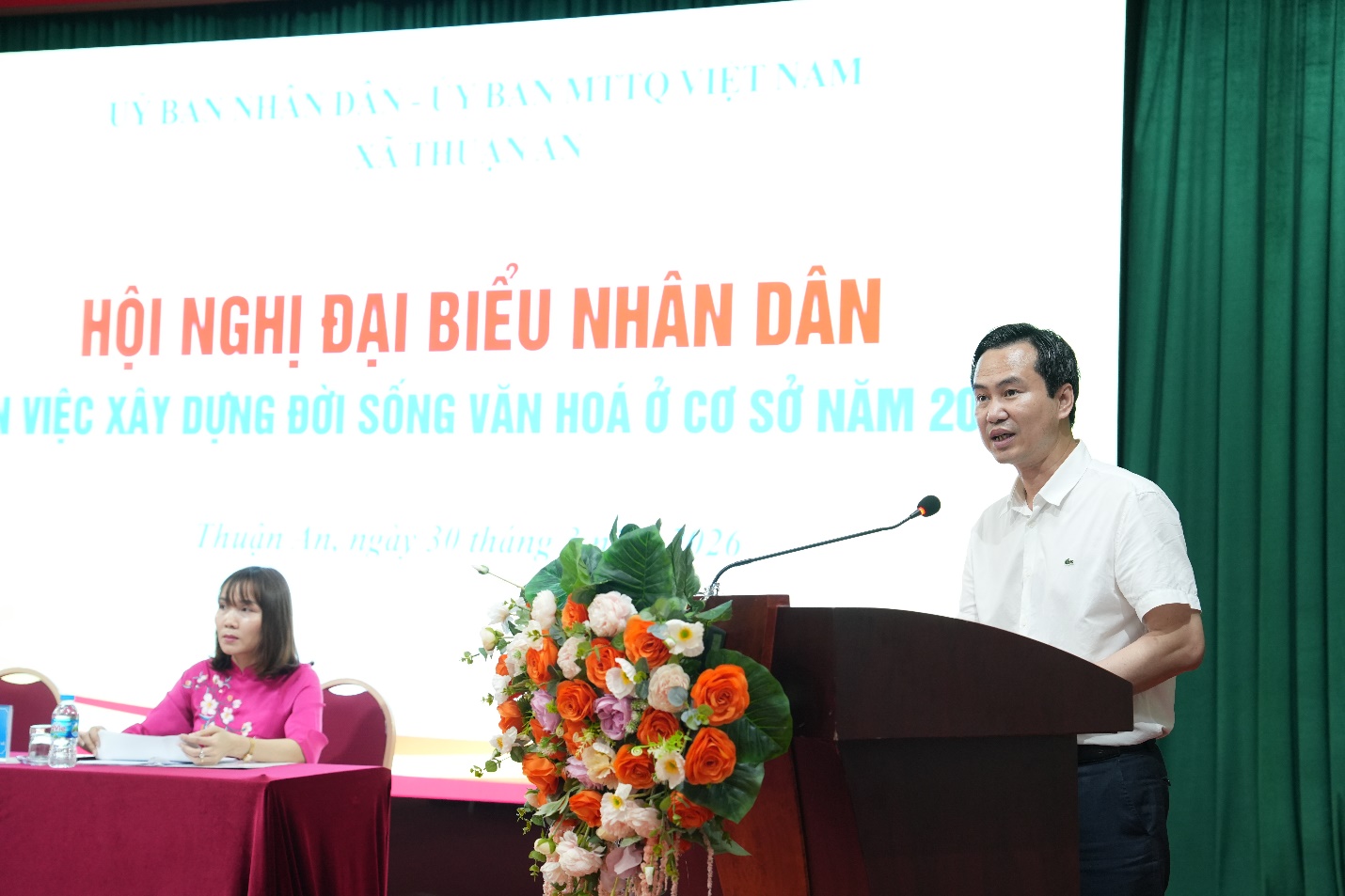 A person standing at a podium with a microphone  AI-generated content may be incorrect.