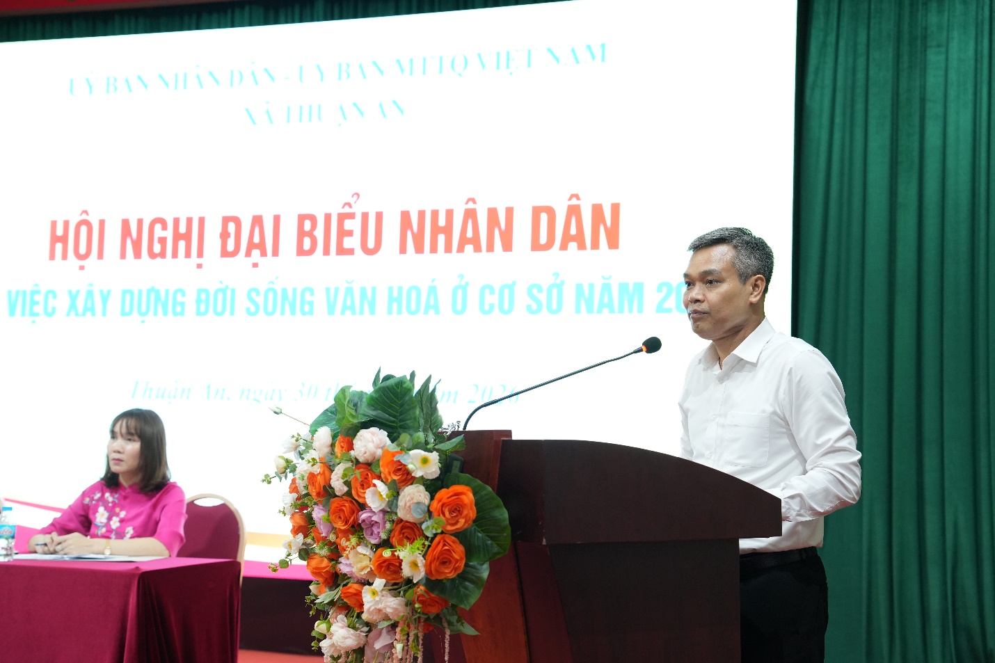 A person standing at a podium with a microphone  AI-generated content may be incorrect.