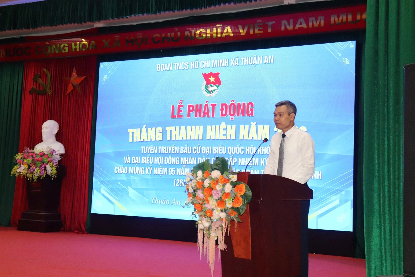 A person standing at a podium with a large screen behind him  AI-generated content may be incorrect.