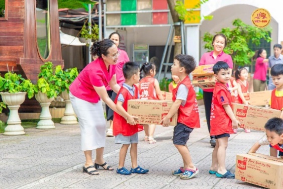 A group of kids holding a box  Description automatically generated