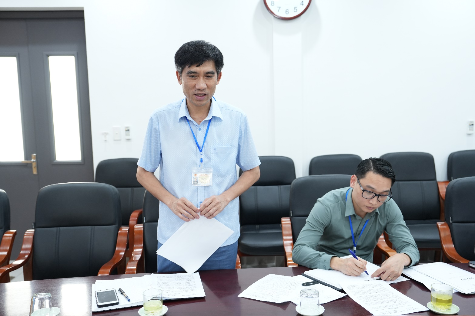 A person standing next to a person holding a piece of paper  AI-generated content may be incorrect.