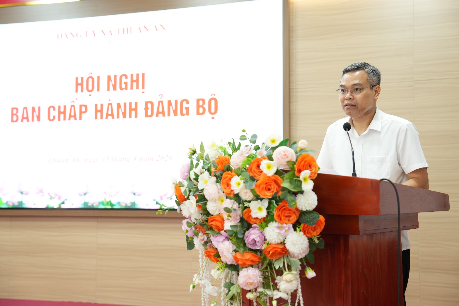 A person standing at a podium with a microphone and flowers  AI-generated content may be incorrect.