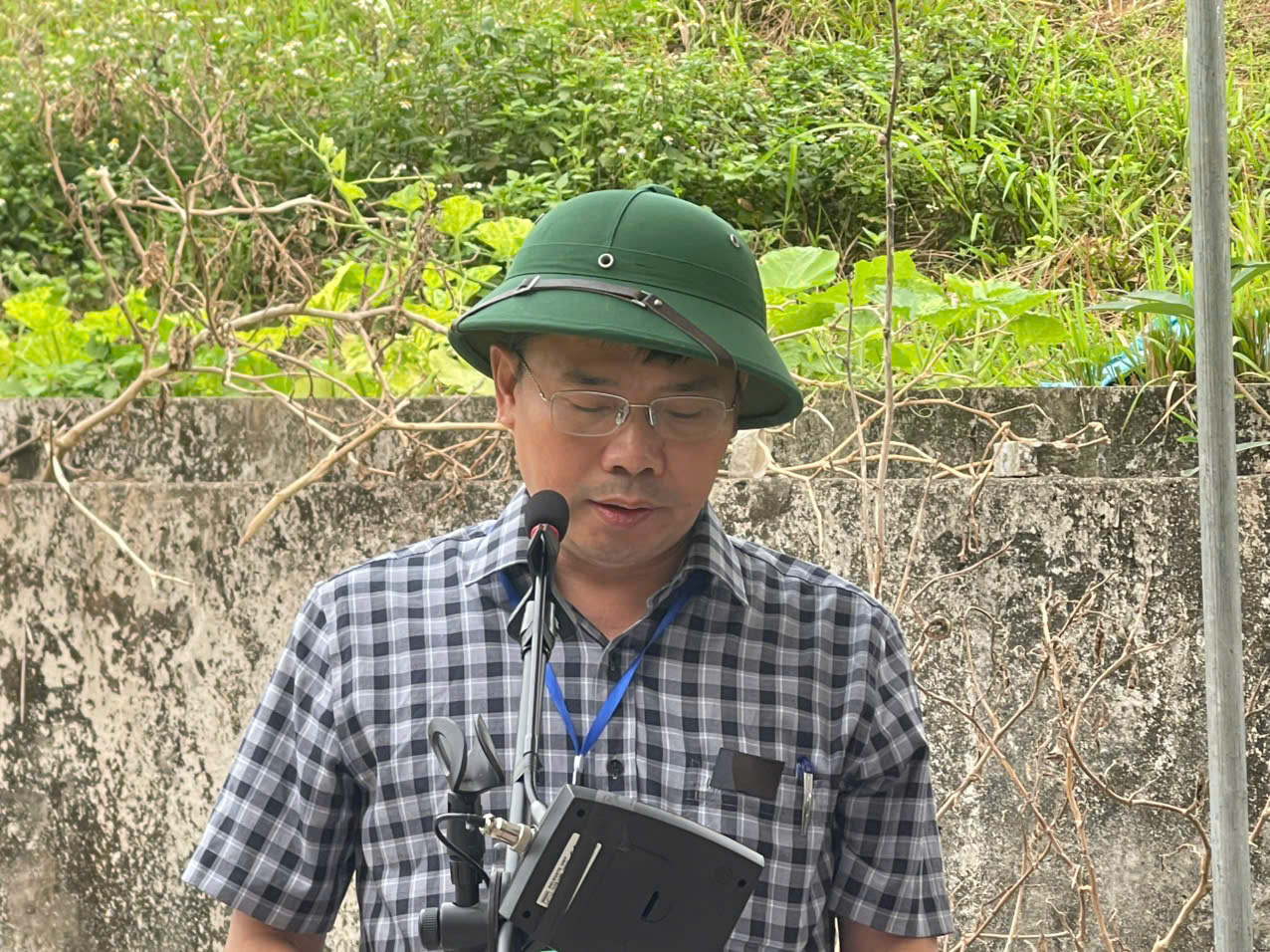 A person wearing a hat and standing in front of a microphone  AI-generated content may be incorrect.