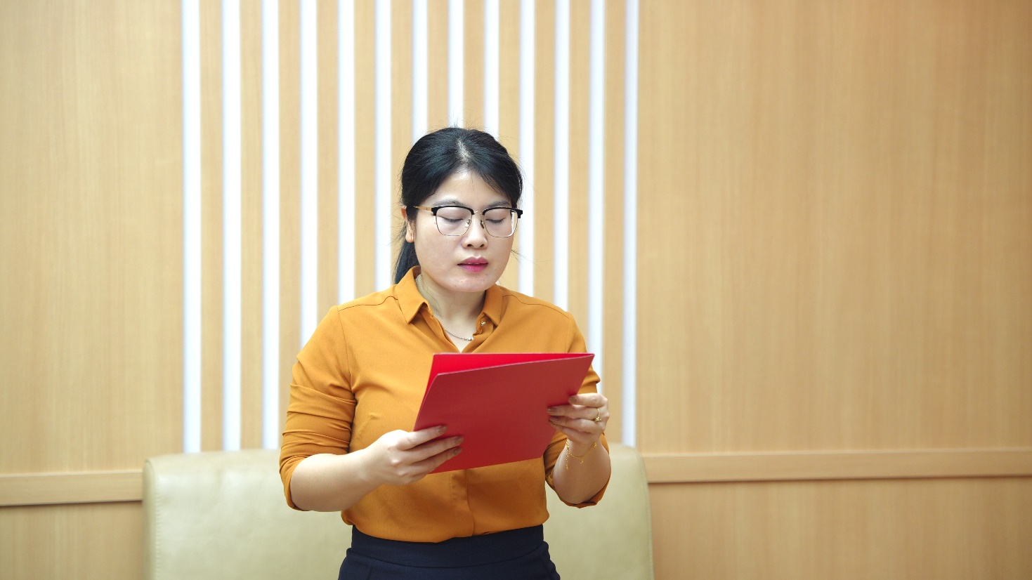 A person in a yellow shirt reading a red folder  AI-generated content may be incorrect.