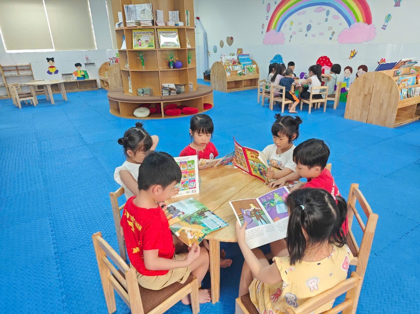 A group of children sitting around a table reading books  AI-generated content may be incorrect.