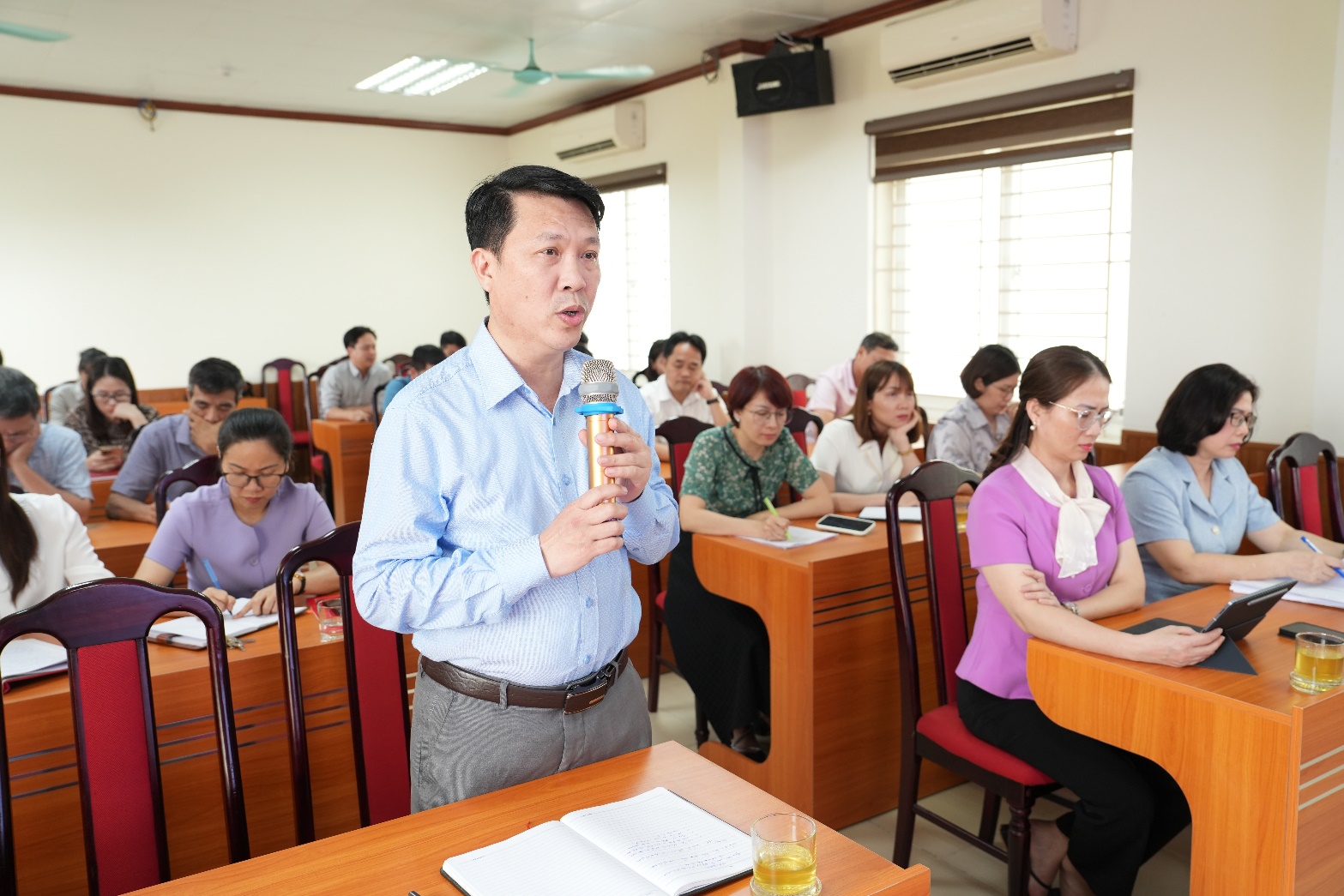 A person standing in a room with a microphone  AI-generated content may be incorrect.