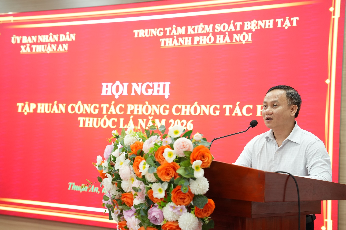 A person standing at a podium with a microphone and flowers  AI-generated content may be incorrect.