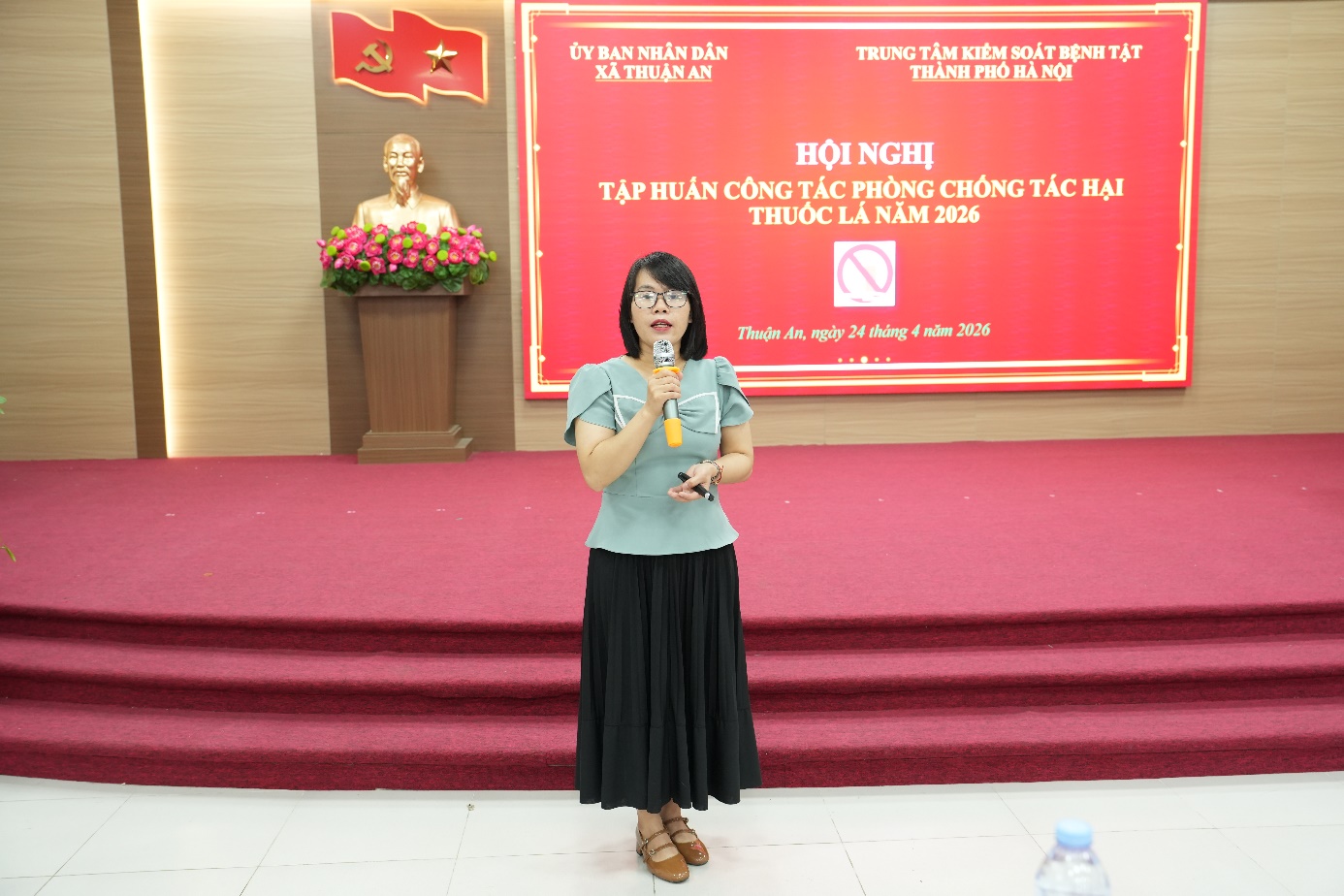 A person standing on a stage holding a microphone  AI-generated content may be incorrect.